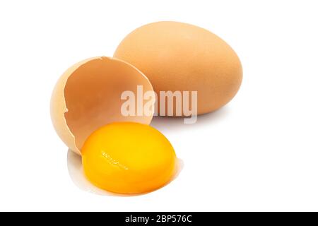 Uova di pollo intere e tuorlo freschi e biologici non cotti versano da metà guscio rotto su sfondo bianco isolato con percorso di ritaglio. L'uovo è proteina alta e. Foto Stock