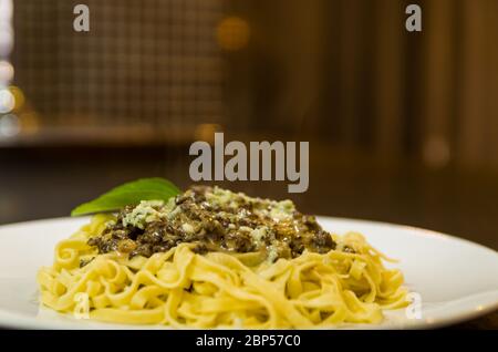 Bella pasta fatta in casa con salsa di carne e gorgonzola formaggio su fondo di pietra nera. Foto Stock