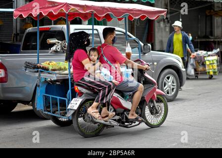 Trasporto della famiglia in Thailandia. Famiglia che cavalcano in un carro di sidecar motociclistico sulla strada per il loro sito come commercianti di mercato di strada. Sud-est asiatico Foto Stock
