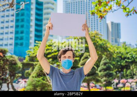 L'uomo in maschera medica previene la malattia del coronavirus tiene un manifesto per le iscrizioni gratuite. SPAZIO DI COPIA Foto Stock