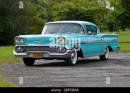 Turquoise 1958 Chevrolet Impala coupé tre quarti di vista frontale contro gli alberi Foto Stock