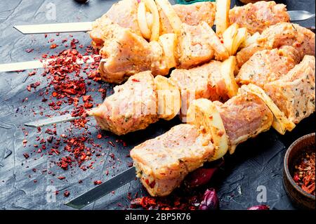 Carne cruda in una marinata barbecue su spiedini di carne non cotta per un picnic.kebab di shish crudo Foto Stock