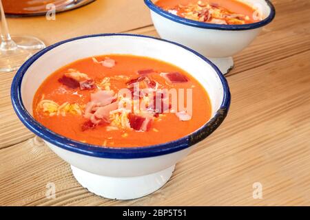 Salmorejo, zuppa spagnola di pomodoro freddo in una ciotola rustica su un tavolo di legno Foto Stock