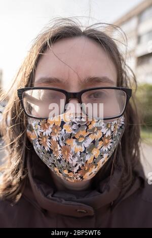 Donna con occhiali fogati perché indossa una maschera medica durante una pandemia. Inconveniente dovuto alla condensa sulle lenti. Foto Stock