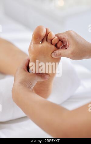 Massaggiate i piedi massaggianti della donna con olio idratante Foto Stock
