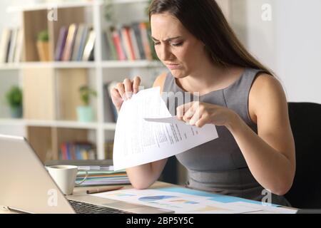 Triste donna imprenditore strappando contratto seduta su una scrivania a casa Foto Stock