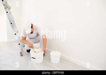 Casa pittore in uniforme bianca su sfondo bianco per la pittura in camera. Foto Stock