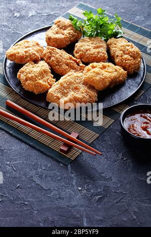 HireKatsu, cotolette di maiale giapponesi su un piatto nero con deliziosa salsa al miso aromatizzante su un tappetino di bambù, vista verticale dall'alto Foto Stock