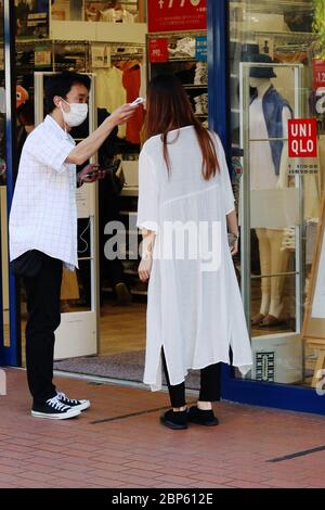 Un membro dello staff controlla la temperatura di un cliente prima che entri in un negozio Uniqlo nella città di Ichikawa durante l'epidemia di coronavirus. Foto Stock