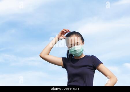 giovane donna asiatica in maschera medica protettiva facendo stretching riscaldamento prima di esercizio al mattino.lavorando all'aperto. Concetto di sano Foto Stock