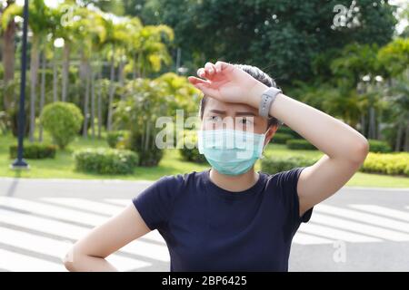 La donna in maschera medica protettiva, si stanca di un riposo di allenamento. Atleta femminile che soffre di mal di testa e vertigini. Foto Stock