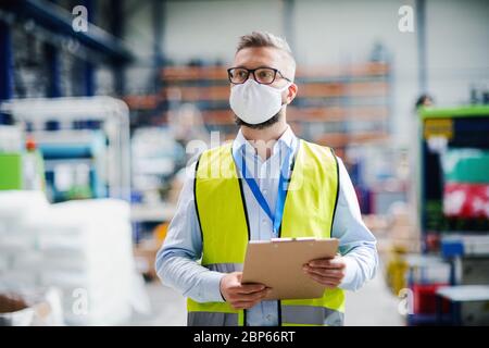 Tecnico o ingegnere con maschera protettiva che lavora in fabbrica industriale, a piedi. Foto Stock