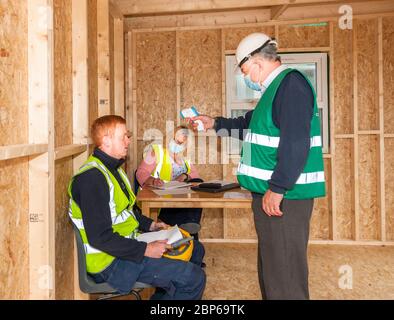 Carrigaline, Cork, Irlanda. 18 maggio 2020.il primo giorno della fase uno con l'alleggerimento delle restrizioni Covid-19 l'ufficiale di sicurezza Michael o'Sullivan assistito da Caroline o'Keffee controlla la tempera dell'elettricista Stephen o' Leary al sito di costruzione Astra a Janeville, Carrigaline, Co. Cork, Irlanda. - credito; David Creedon / Alamy Live News Foto Stock