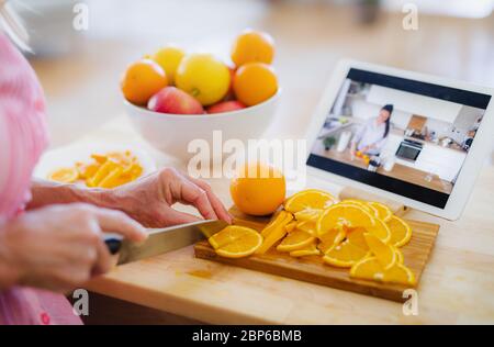 Donna irriconoscibile che prepara il cibo in cucina al chiuso, seguendo vlogger cibo. Foto Stock