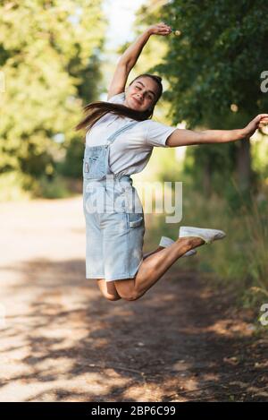 La ragazza in tuta salta con le gambe incrociate. Foto Stock