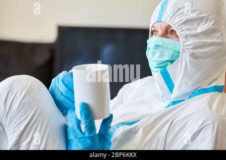 Il personale infermieristico in clinica in abbigliamento protettivo si rompe con la tazza sul pavimento durante l'epidemia di coronavirus Foto Stock