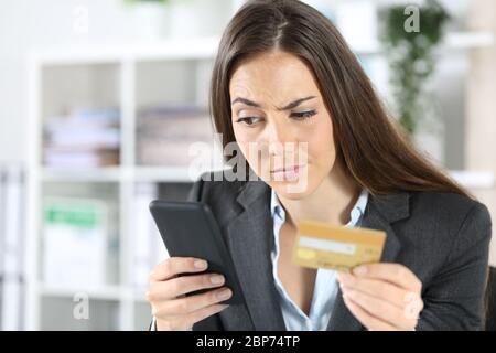 Donna dirigente sospetta paga con carta di credito su smartphone seduto in ufficio Foto Stock