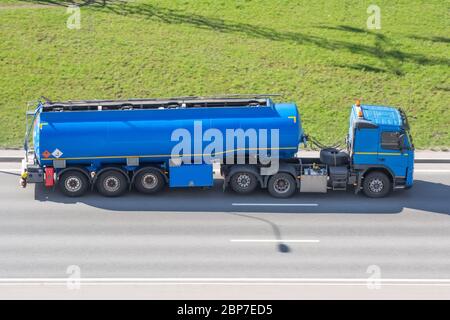 Grande autocisterna con serbatoio blu a zoppo che guida sull'autostrada della città, vista aerea laterale Foto Stock