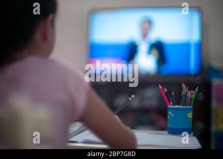 Bambina piccola ragazza imparare su DLTV o a distanza apprendimento Televisione a casa, distanza sociale durante la quarantena, concetto di formazione online Foto Stock