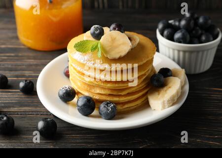 Composizione con frittelle, banana, mirtillo e marmellata su sfondo di legno Foto Stock