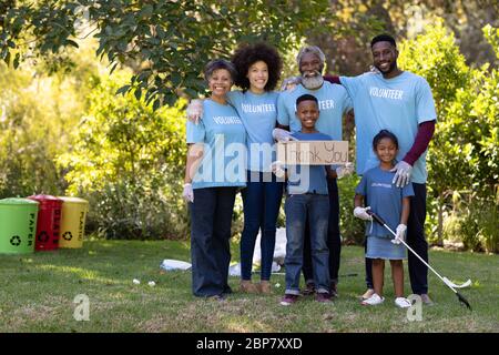 Famiglia multigenerata che raccoglie rifiuti con un ragazzo che tiene un segno scritto grazie Foto Stock