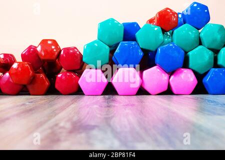 i manubri multicolore si trovano sul pavimento in palestra, sullo sfondo, Foto Stock