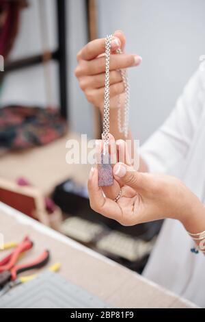 Immagine ravvicinata di una donna che mostra una grande pietra di quarzo rosa sulla catena d'argento Foto Stock