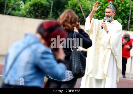 Roma, Italia. 18 maggio 2020. Prima messa in due mesi celebrata nella chiesa di Santissimo Sacramento, nel quartiere sud-est di Roma. Poiché le misure di allontanamento sociale permetterebbero pochi fedeli all'interno della chiesa, il sacerdote, Don Maurizio Mirilli, celebra la messa nel campo di calcio adiacente. Roma 18 maggio 2020. Covid-19 Italia rilassa ulteriormente il blocco. Oggi un decreto del Consiglio del Ministro permetterà la riapertura di quasi tutte le attività. Negozi di abbigliamento, centri commerciali, parrucchiere e chiese per servizi religiosi. Photo Samantha Zucchi Insifefoto Credit: Insifefoto srl/Alamy Live Foto Stock