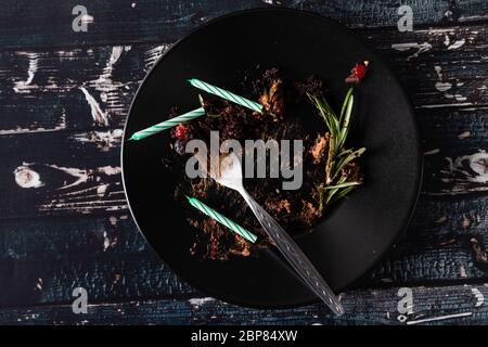 piatto nero con frulente confessato dalla torta con candele Foto Stock