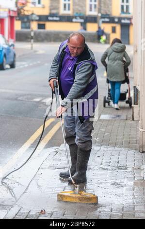 Bandon, West Cork, Irlanda. 18 maggio 2020. Bandon ha fatto pulire la strada principale questa mattina, come parte della fase di 'ritorno al business' di uscire dal blocco Covid-19, Soft Clean Group è stato incaricato di eseguire il compito a Bandon. Robert Healy, un dipendente, pulisce la strada con un panno morbido. Credit: Notizie dal vivo di AG/Alamy Foto Stock