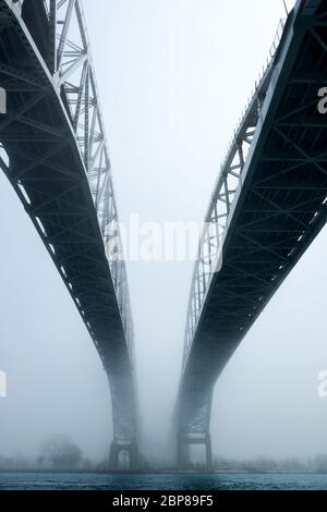 Nebbia che circonda la doppia campata di ponti sul fiume. Percorso che porta a un futuro sconosciuto di uscire dalla nebbia. Foto Stock