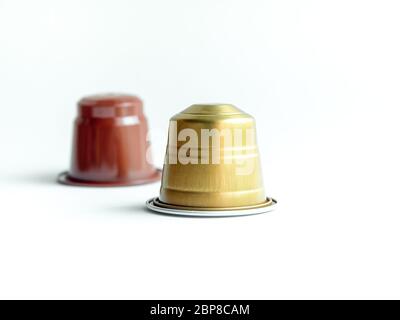 Capsule di caffè espresso dorate e marroni su sfondo bianco. Foto Stock