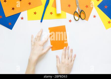 Come facile fare carta adorabile divertente pesce giocattolo con i bambini a casa. Istruzioni dettagliate. Mani che fanno la fabbricazione estiva fai da te. Vista dall'alto. Fase 2 Foto Stock