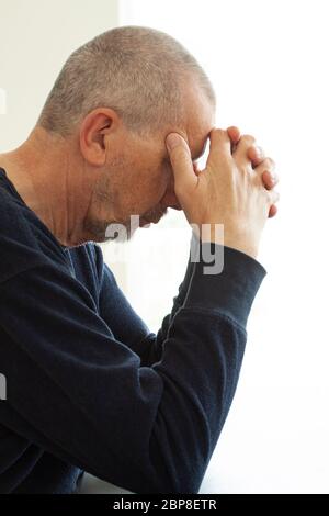 Infelice depresso maschio seduto da un tavolo stressato dal lavoro, ansia, cuore rotto e concetto di assistenza sanitaria. Primo piano verticale. Foto Stock