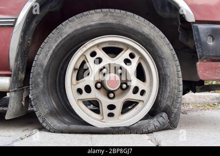 Auto abbandonata sulla strada. Pneumatico sgonfio e rottura pneumatici Foto Stock