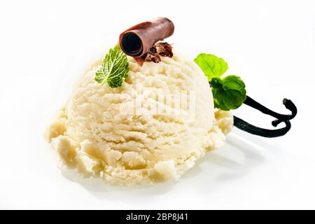 Uno scoop di cremoso gelato alla vaniglia decorato con verde di foglie di menta piperita e guarnita con scaglie di cioccolato Foto Stock