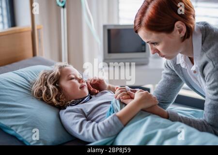 Madre che si prende cura di visitare la figlia di bambina in letto in ospedale. Foto Stock