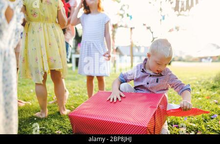 Sindrome di Down bambino con amici in festa di compleanno all'aperto in giardino. Foto Stock