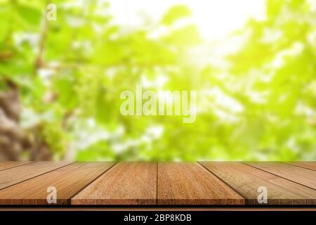 Tavolo vuoto in legno su sfondo verde sfocato per l'esposizione del prodotto. Foto Stock