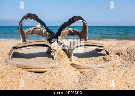 Sandali da primo piano sulla sabbia della spiaggia. Scarpe sportive estive. Escursioni, attività all'aperto. Il concetto di turismo e di viaggio. Foto Stock