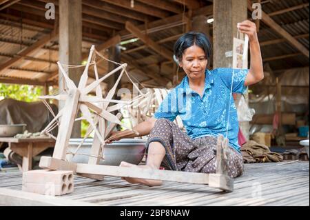 Donna che gira la seta su una ruota che gira tradizionale. Silk Island, Phnom Penh, Cambogia, Sud-est asiatico Foto Stock