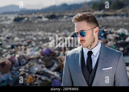 Uomo d'affari moderno in discarica, consumismo contro concetto di inquinamento. Foto Stock