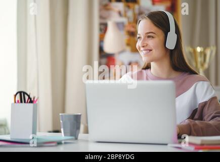 Giovane studentessa seduto al tavolo, utilizzando il laptop quando studia. Foto Stock