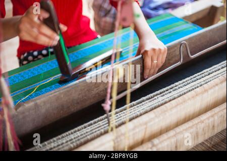 Primo piano delle mani della donna che tessono seta su un telaio di tessitura tradizionale. Silk Island, Phnom Penh, Cambogia, Sud-est asiatico Foto Stock