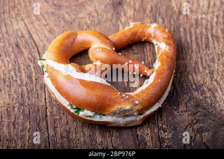 Pretzel bavarese con burro su legno Foto Stock