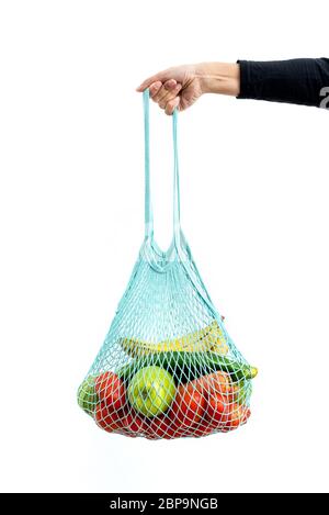 Ragazza che tiene una borsa riutilizzabile in rete piena di verdure biologiche Foto Stock