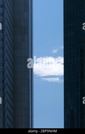 Una nuvola e il cielo blu tra gli angoli e i bordi laterali di due moderni grattacieli. Foto Stock