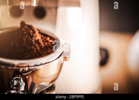 Primo piano della macchina da caffè Barista per macinare un lotto di chicche di caffè fresche. Foto Stock
