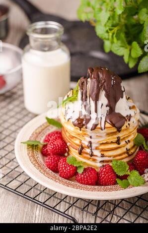 Frittelle americane con icecream e cioccolato, erbe e bacche intorno Foto Stock