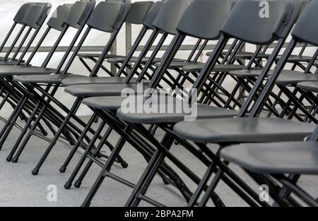 Numerose sedie pieghevoli disposte in una fila in una sala conferenze. Foto Stock